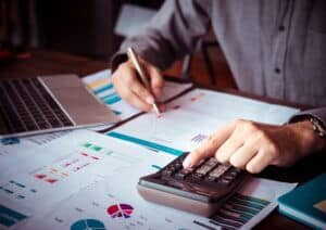 Personne calculant un budget avec des tableaux financiers.